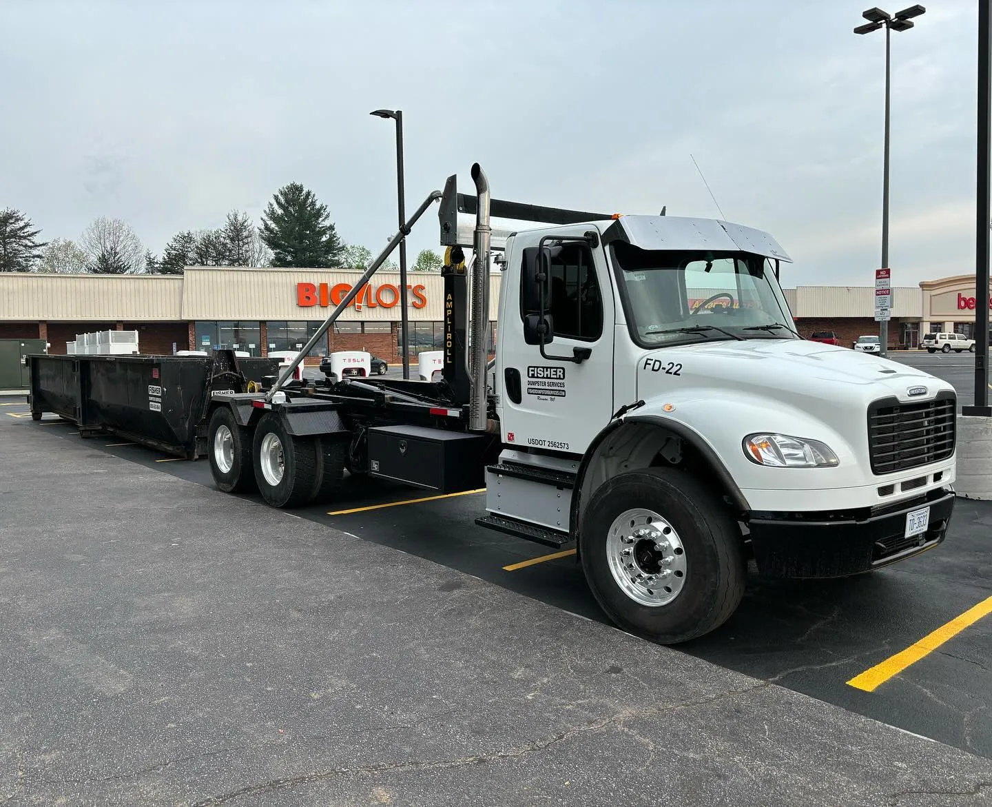 White truck with a dumpster attachment parked in a retail lot in Murphy, NC.