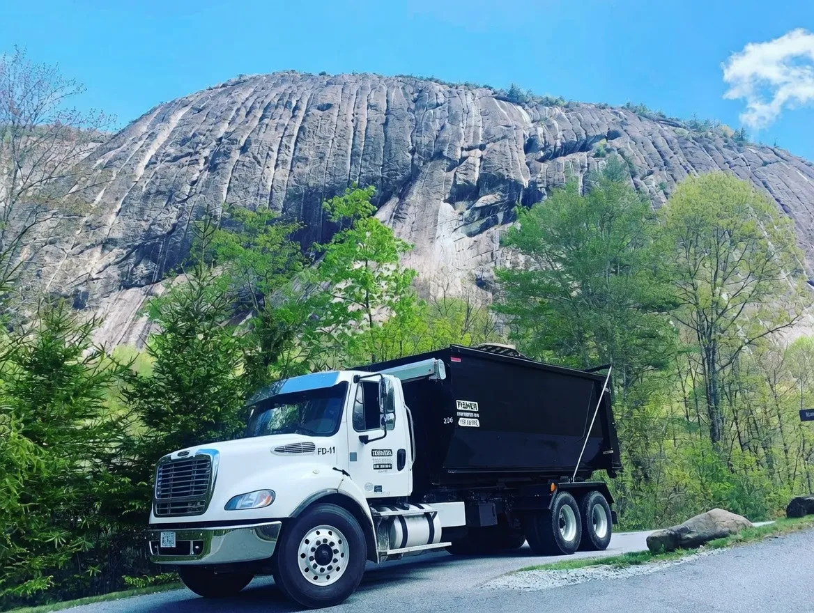 Dump truck parked beside a large rocky cliff and green trees near Haywood County, NC