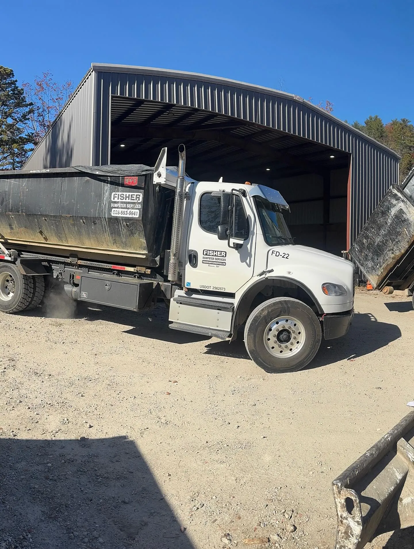White Fisher Dumpster Services truck parked outside a metal storage building near Murphy, NC